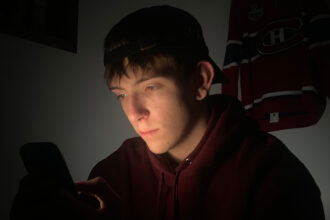 Un jeune Québécois consulte des plateformes de paris sportifs, un phénomène amplifié par les influenceurs et réseaux sociaux.